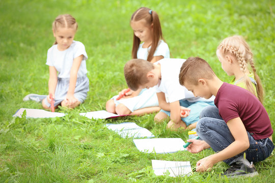 Cute little children drawing pictures on green grass