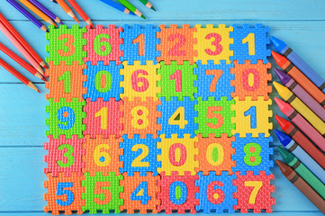 Math puzzle, pencils and crayons on blue background