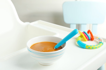 Bowl with baby food on highchair