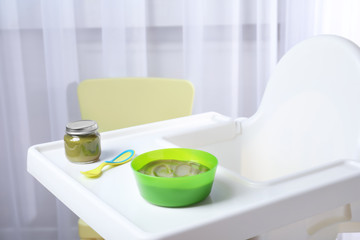 Bowl with baby food on highchair indoors
