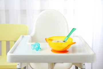 Bowl with baby food on highchair indoors