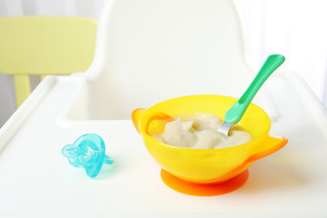 Bowl with baby food on highchair