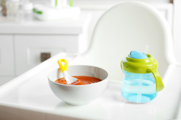 Bowl with baby food on highchair indoors