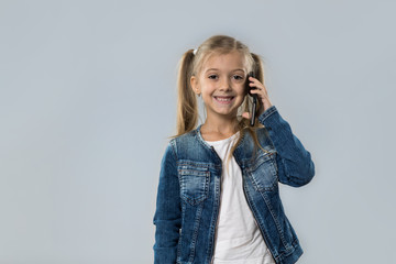 Beautiful Little Girl Speak Cell Smart Phone Call Happy Smiling Wear Jeans Coat Isolated Over Gray Background