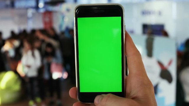 man using tapping touchscreen close up smartphone green screen chromakey people hall background pointing finger digital appliance mockup internet browser connection website apps notification map gps