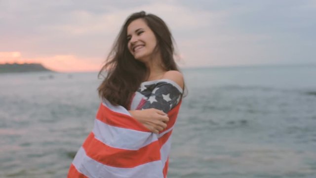 young beautiful female on beach during sunrise with USA flag. 4th july concept
