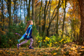 beautiful little girl is playing and running in the autumn park.