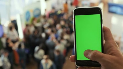 male man hand using smart phone tapping empty mockup display green screen chromakey blur crowd queue people line business event hall internet provider networking checking notification apps webpage 3g
