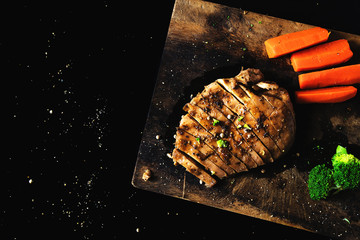 Steakchicken carrots and broccoli on a chopping board is roast until fragrant, tasty. With light and shadow on a piece of chicken.