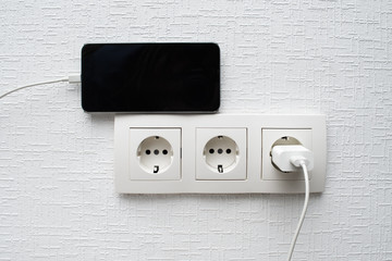 European set of sockets on the wall with mobile phone charging