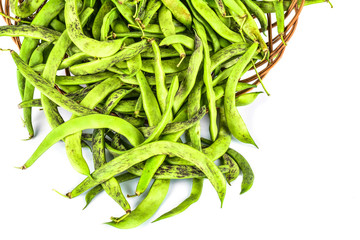 Green bean pods in wicker basket on white background