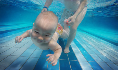 Baby background. Happy infant learn to swim, dive underwater with fun in pool to keep fit.