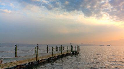 Fototapeta premium the wooden pier stretching into the sea cloudy sunset.