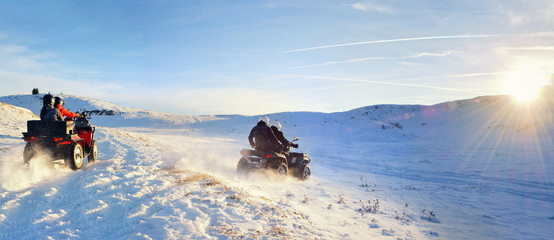 Group of female and man driving quad bike on top of the mountain at sunset