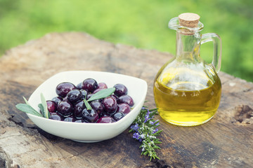 Olives in bowl and rosemary on black background