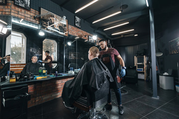Plakat brutal hairdresser/ Barber cutting in barbershop. Hairdresser at work