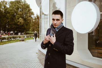 man coat and scarf/ Stylish handsome man in a coat and scarf at a showcase on a city street