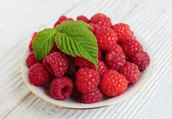 Raspberries in a bowl on a wooden white table