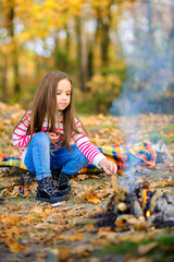 happy girl frying marshmallows on fire, trekking in the forest.