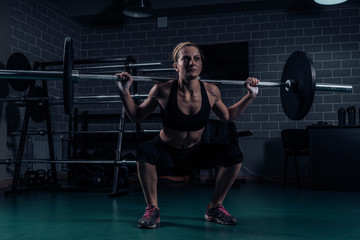 Fototapeta na wymiar Crossfit Muscular strong woman crouching with heavy weight in the gym