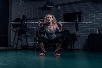 Fototapeta na wymiar Powerful woman athlete doing squats with heavy weights. cross-training