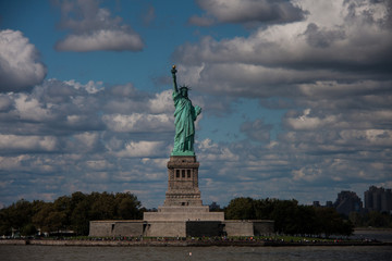 Fototapeta premium Postcard from New York: Statue of Liberty against cloudy sky on sunny day, Liberty Island