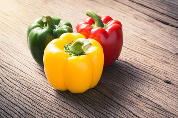 three colors of sweet bell pepper on old wooden space background ( Capsicum annuum., SOLANACEAE )