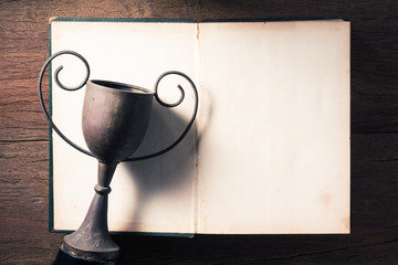 Vintage trophy and blank opening page of old book on old wood table