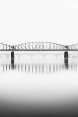 Foggy winter mood at Vltava river. Reflection of bridges in water. Black and white atmosphere, Prague, Czech republic
