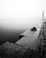 Fototapeta premium Foggy autumn mood at Vltava river. Detail of riverbank. Black and white atmosphere, Prague, Czech republic