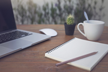 Wooden table with notepad, computer and coffee cup. View from above with copy space.