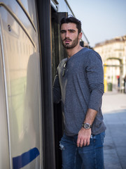 Young handsome man looking at camera while walking in bus on street.