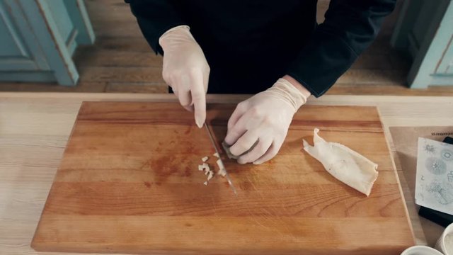 Cook hands is slicing of boiled squid. One of the stages of cooking calamaries. seafood restaurant top view