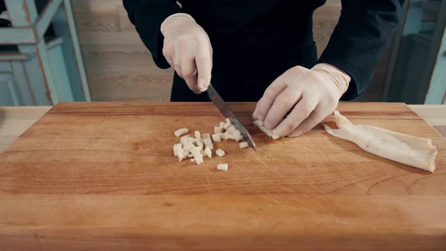 Cook hands is slicing of boiled squid. One of the stages of cooking calamaries. seafood restaurant top view