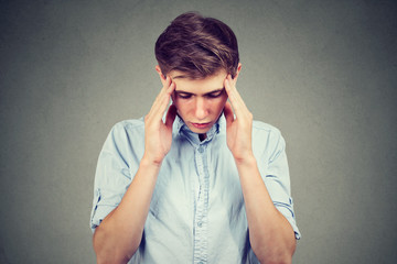 Sad young handsome man with worried stressed face expression looking down