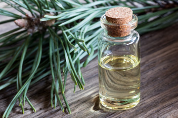 A bottle of pine essential oil with pine branches in the background