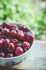 Bowl with ripe cherries on the rustic background. Shallow depth of field.