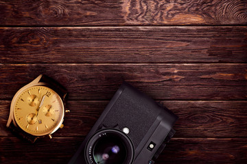 Fototapeta premium retro camera with wrist watch on the brown wooden background
