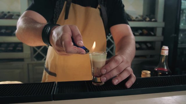 bartender prepares B52 Shot, cocktail preparation in modern bar with fire, tequilla vodka rum gin
