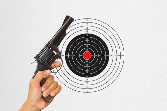 Hand holding black gun with shooting target background