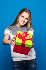 Portrait of a happy smiling girl holding present box and winking isolated over blue background