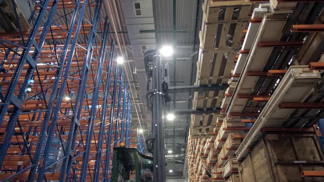warehouse worker driver in uniform loading cardboard boxes by forklift stacker loader furnirure storage boards