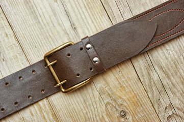 leather belt with a buckle on a wooden board