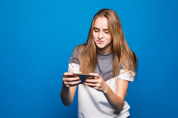 Fototapeta premium Woman play game on phone on blue background