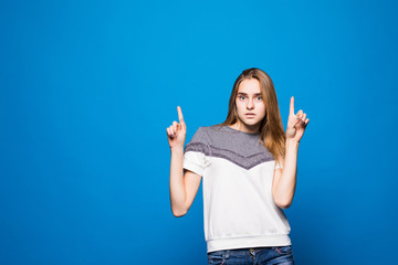 Portrait of beautiful young woman pointed up against blue background