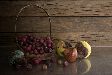 Still Life image of rot fruits in the basket on old glass