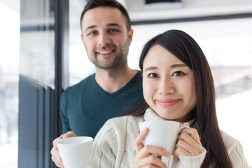 multiethnic couple enjoying morning coffee by the window