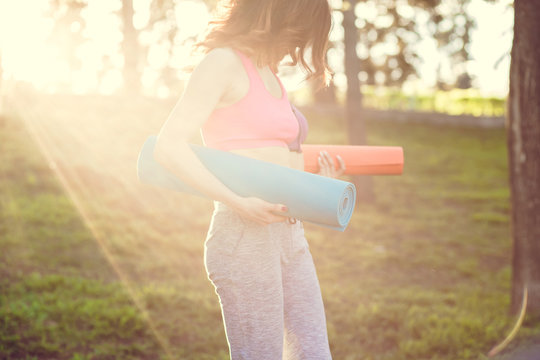 Woman Walking With A Yoga Mat Outside Wearing Sports Wear And Doing Yoga