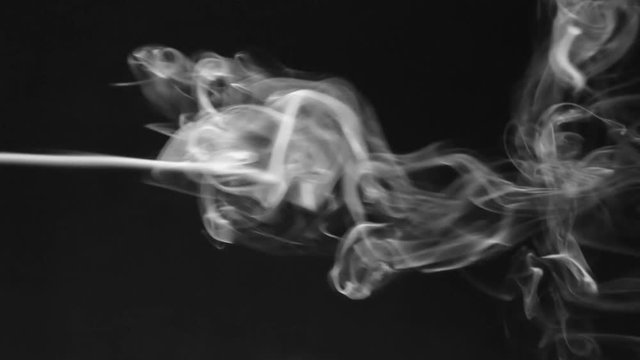 Stream of white smoke turning into smoke puffs on a black background.