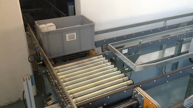 Plastic boxes moving in industrial warehouse.